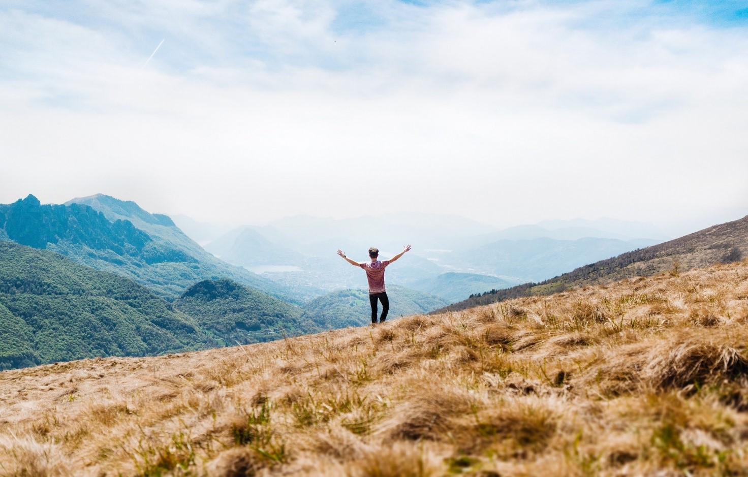 a person standing with his arms above his head chearing, as he if he is free just because he is standing in a field in the middle of nowhere